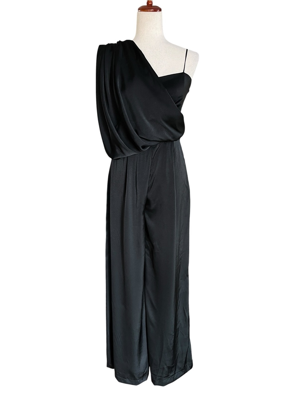 DO+BE black satin jumpsuit featuring an asymmetrical draped one-shoulder overlay